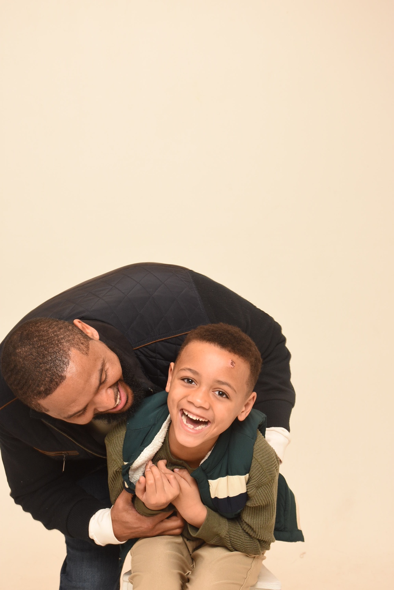 Father leaning over his smiling son in a playful pose