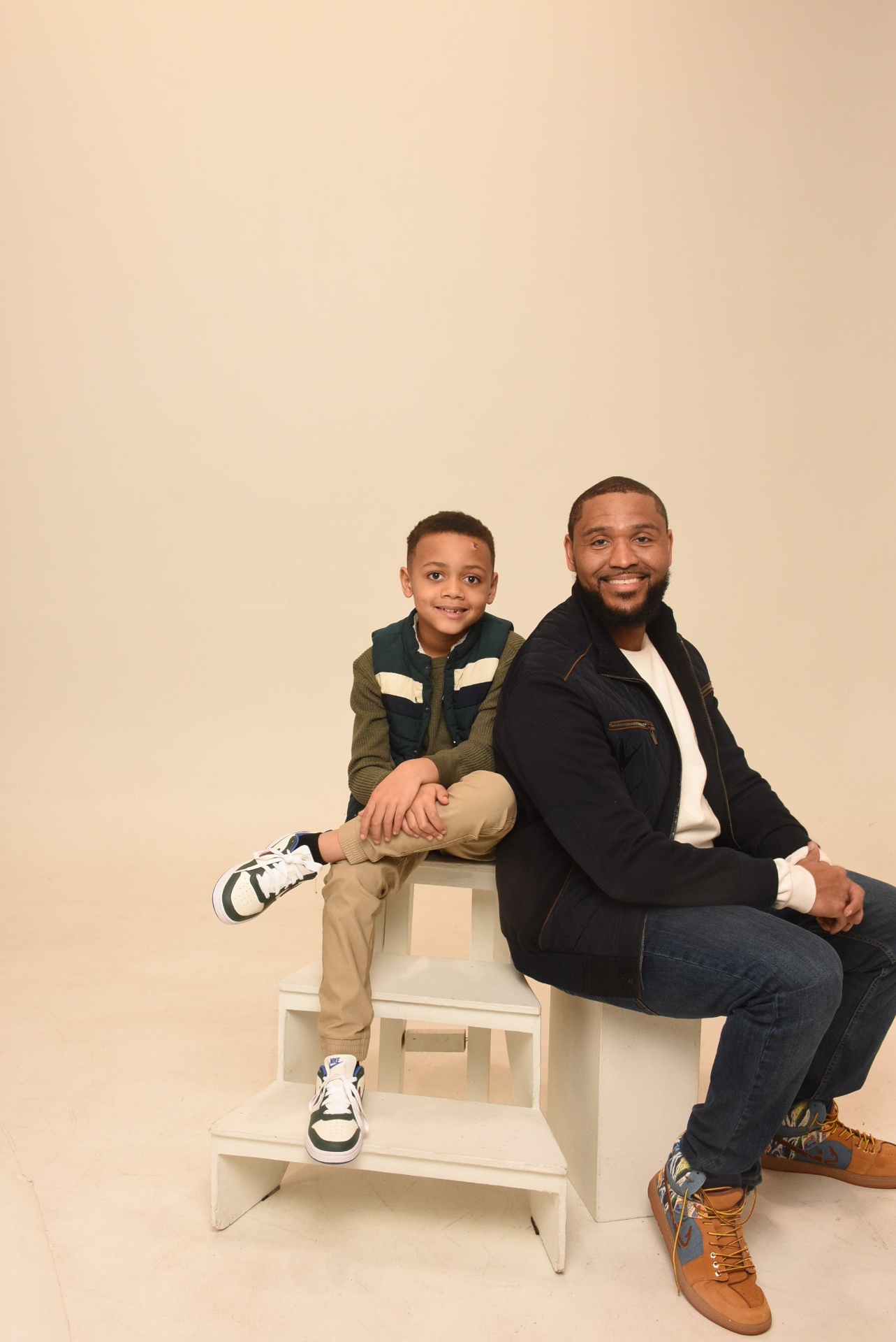 Father and son sitting together on a studio stool